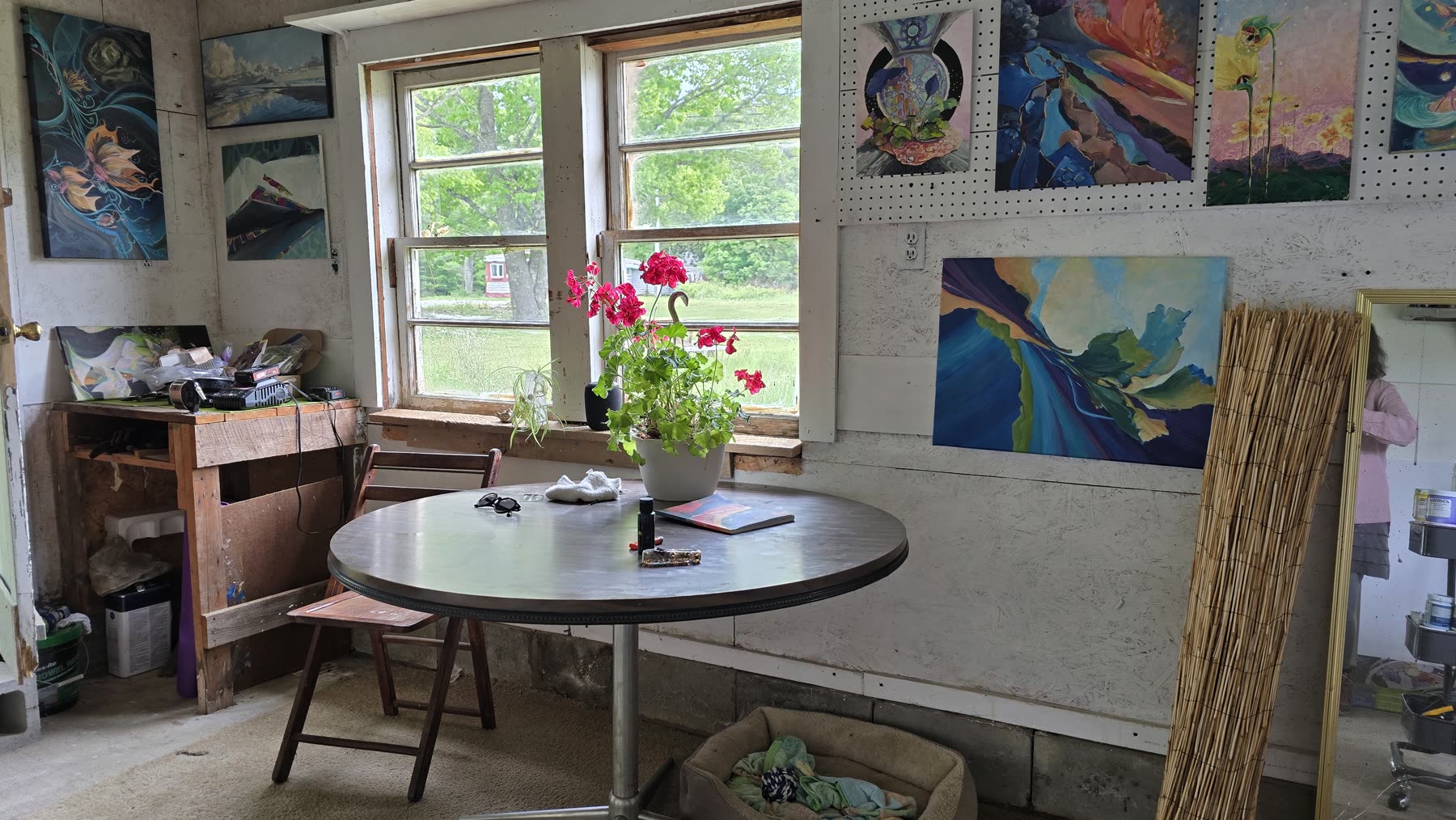 Inside Pajaritaflora Studio with paintings, windows, and a round table with red flowers